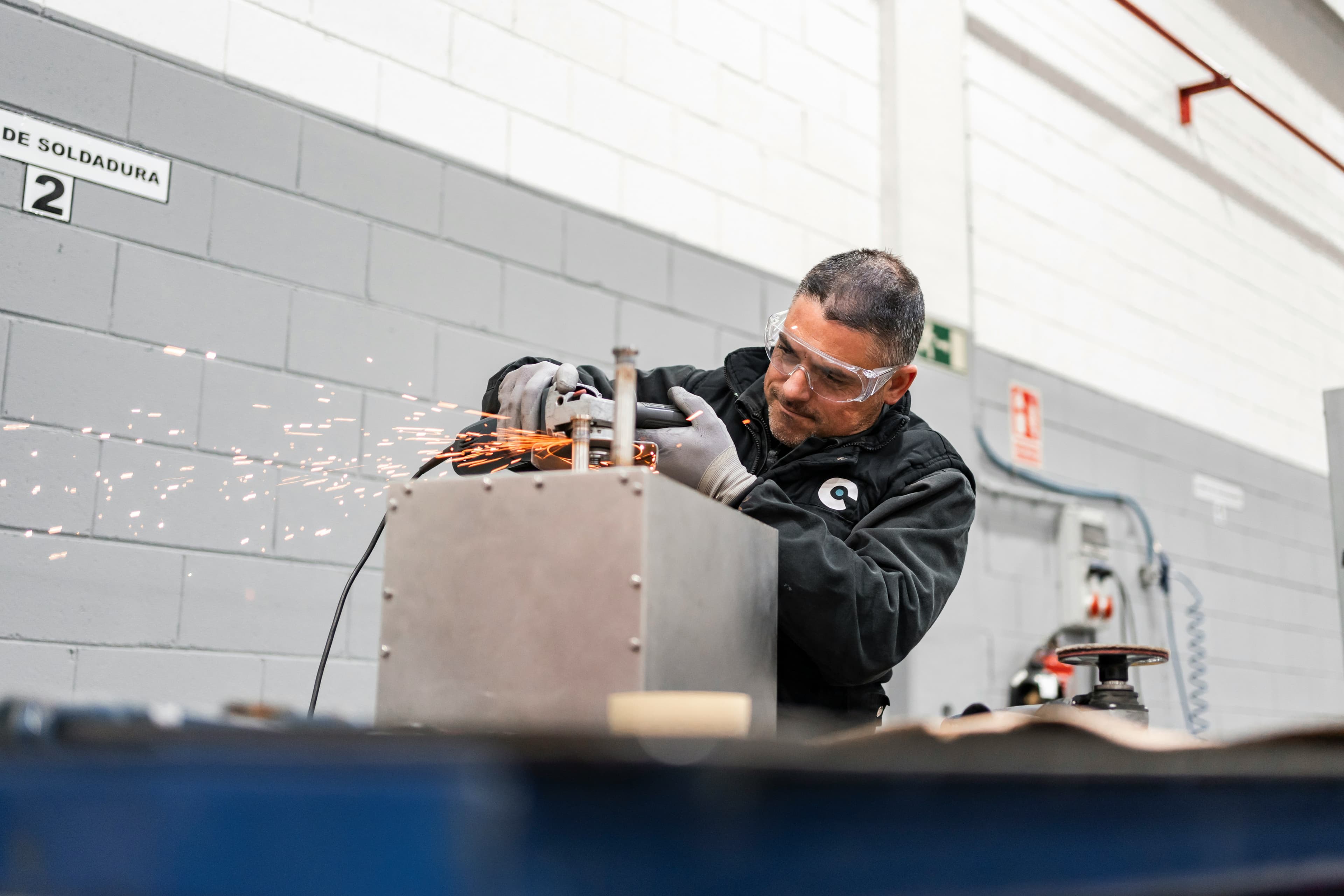 Workshop technician grinding metal during production