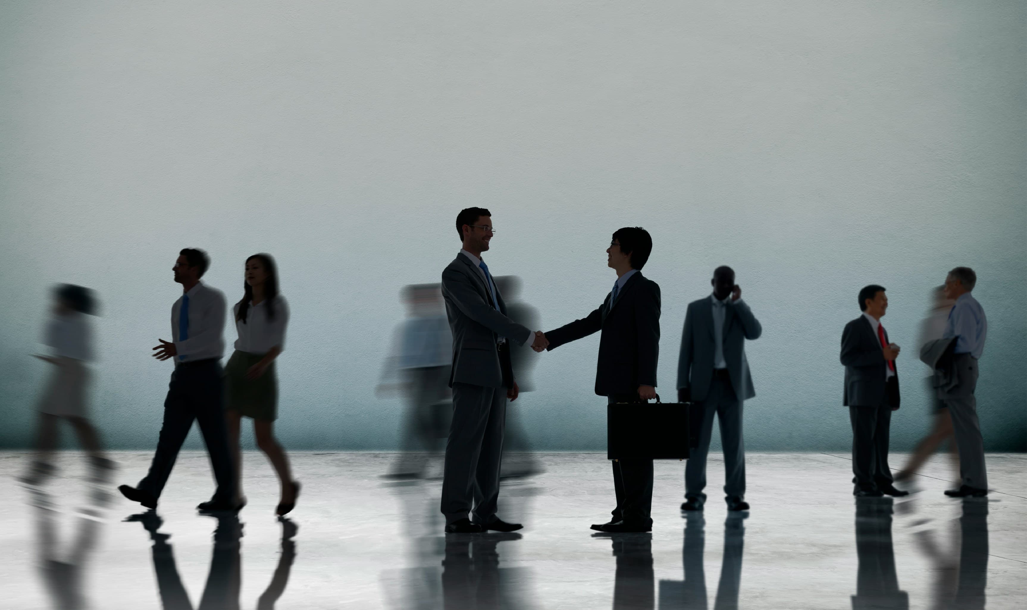 Business partners shaking hands in a busy office hall